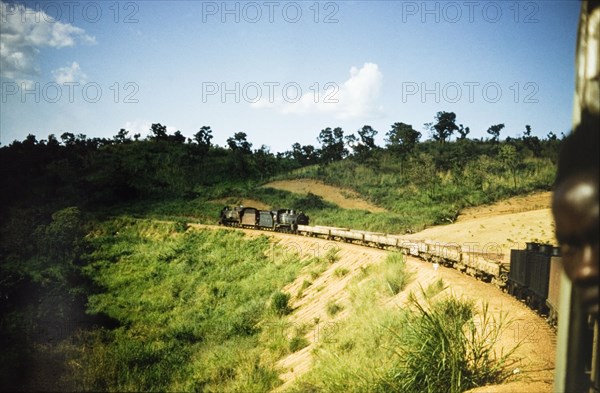 Freight cars on the Western Ugandan Extension. A steam locomotive pulls a line of freight cars around a bend on the Western Ugandan Extension, a section of railway track built to transport partially refined copper ore down country. Kamwenge, West Uganda, 1957., West (Uganda), Uganda, Eastern Africa, Africa.