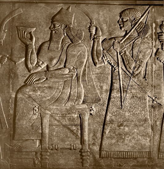 The king, Ashurnasirpal is seated between two attendants