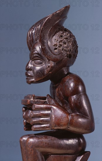 Chief holding a sanza, a musical instrument of the ideophone family, with metal keys and gourd resonator
