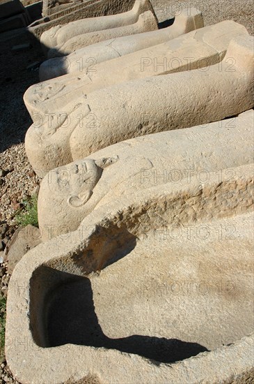 Row of empty carved stone sarcophagi in the courtyard of the Temple of Hathor