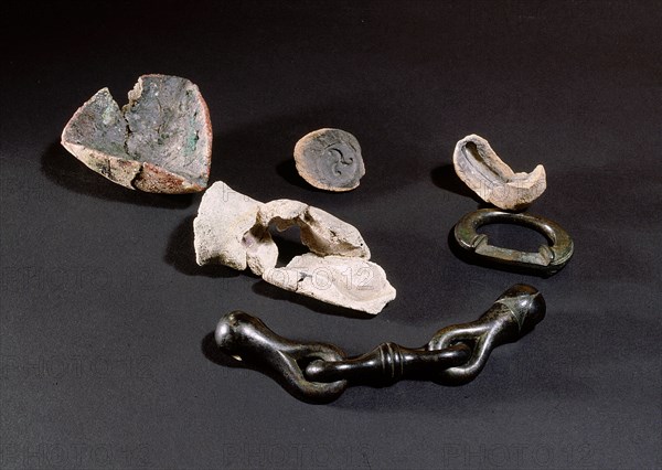 Left to right: triangular crucible used for melting bronze, two moulds, one for making a horses bit (also shown), a terret (guiding ring) and above that a fragment of a mould used for casting a decorated object of this type