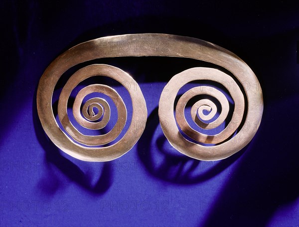 Gold spiral breast ornament thought to be a schematic representation of an owls face