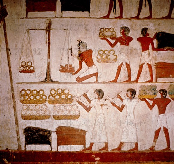 A detail of a wall painting in the tomb of Panekhmen depicting metal workers weighing gold on scales