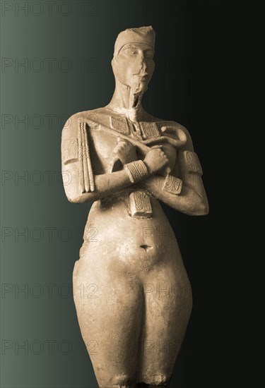 Colossal statue of Akhenaten standing with arms folded holding the flail and heka scepters