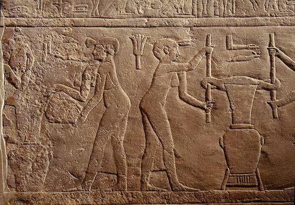 Bas relief from the tomb of Pairkep showing servant women squeezing oil from lilies in a press for use in perfume