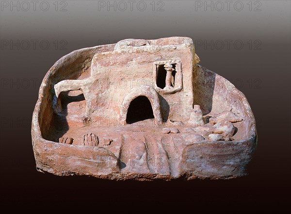 A model of a house with a rounded door and a staircase to the roof which has a vent to catch the cool breeze