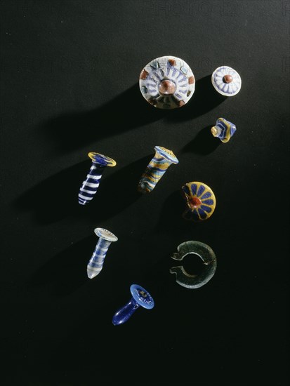 A selection of ear ornaments   glass papyrus column pendants, glazed composition studs and earrings, all worn on wire
