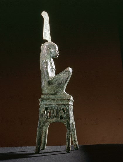 Seated bronze figure of the goddess Maat, wearing a tripartite wig, seated on an openwork throne of winged uraei and Hathor heads