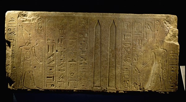 Queen Hatshepsut represented as a male pharaoh, on the left, presents twin obelisks to the God Amun