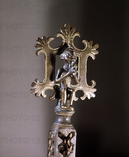 The top of a staff with a figure representing Christ on the Cross