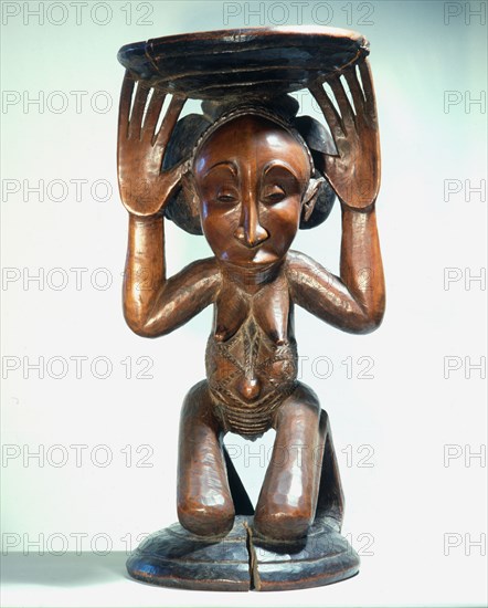 Chiefs stool supported by kneeling woman