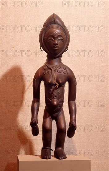 A wood figure of a young woman with decorative scarifications, holding two gourd containers