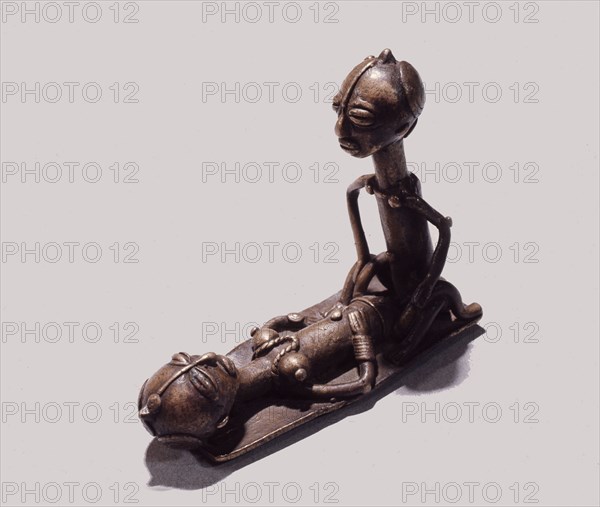 A brass weight which was used for weighing gold dust, representing a man and woman during sexual intercourse