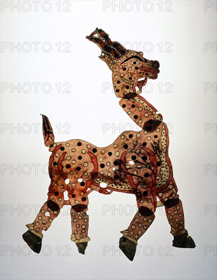 A shadow puppet in the form of a yellow prancing horse, decorated with black and white spots