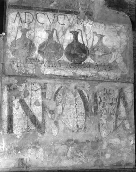 A wine shop sign in the main street, advising to come to the sign of the bowls (ad cucumas)