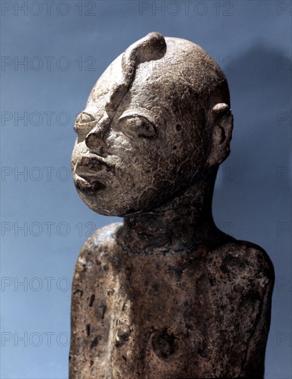 A terracotta figure with a snake curling down the forehead