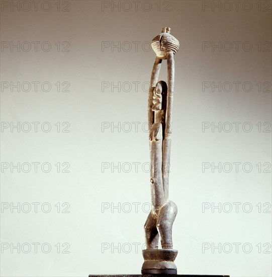 A Dogon sculpture with upraised arms holding a bowl