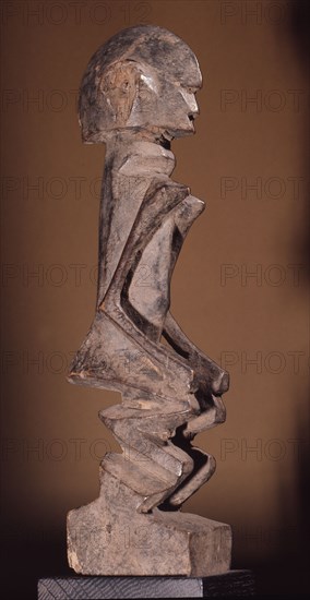 A wood sculpture of a woman, possibly an ancestor figure