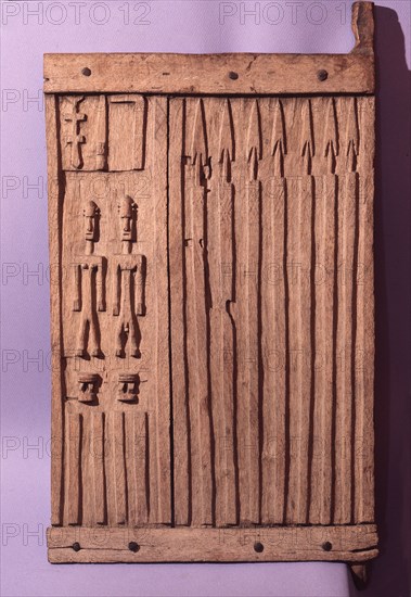 A shutter like door from a Dogon granary sculpted with rows of spears, two stools and a couple which may refer to the founding ancestors of the owners family or village