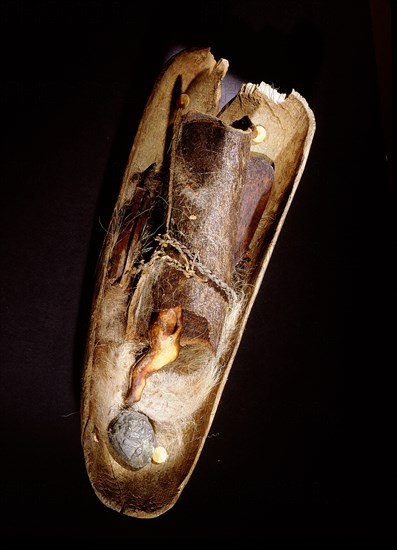 A wooden bowl containing artefacts, including a sea mammal ivory figure, used by a shaman in healing procedures