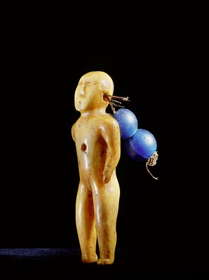 Small ivory carving of a human adorned with blue beads