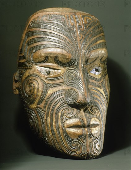 A carved wood Maori head with inlaid shell eyes