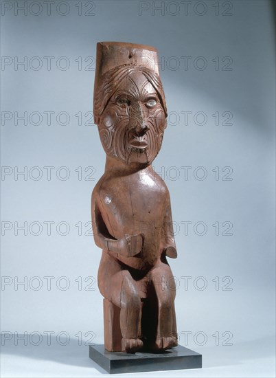 A seated Maori figure with moko facial tattoos