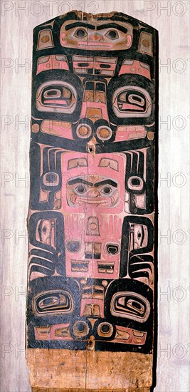 A carved and painted cedar board with a design showing ancestry and social position