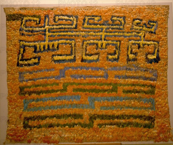 Featherwork tabbard depicting a combination of a tumi knife in the shape of a crescent, two bicephalic dragons and radiant sun faces