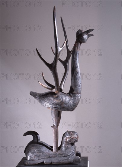 Sculpture of a phoenix with spread wings in the form of deer antlers, resting on a reclining tiger