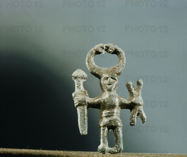 Pendant or amulet of a man holding a sword and two spears and wearing a horned helmet