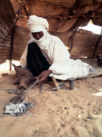 A blacksmith, possibly Tuareg or Songhay, forging iron