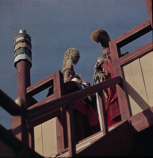 Lamas calling the faithful to morning prayers by blowing conch shells