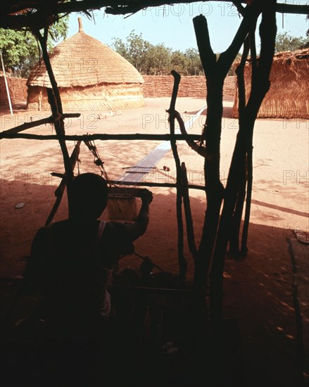 Weaving on the horizontal double heddle loom typical of West Africa