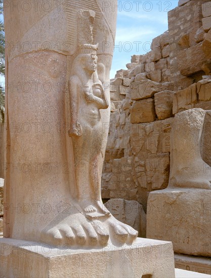 A princess, perhaps Bentanta, standing at the feet of a colossal statue of her father Ramesses II