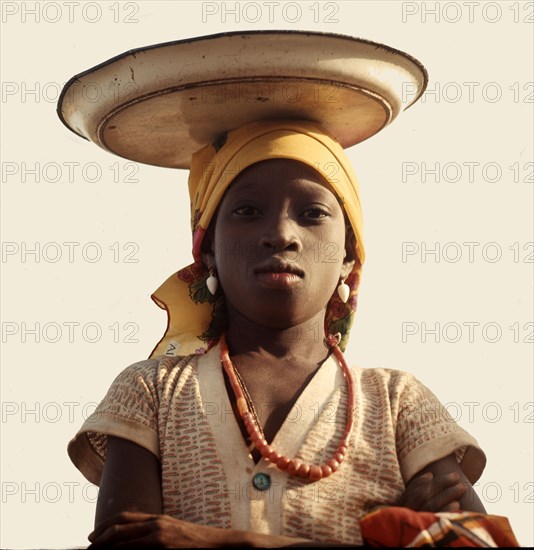 A Yoruba girl carrying her small stock of trade goods on her head