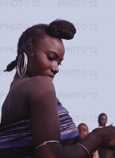 A woman wearing her hair in a distinctive style peculiar to her sub-division of the pastoral Fulani