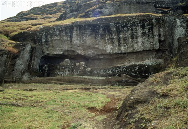 Two giant Easter Island moai statues lying head-to-foot, unfinished, and still attached to the bedrock of the volcanic Rano Raraku quarry