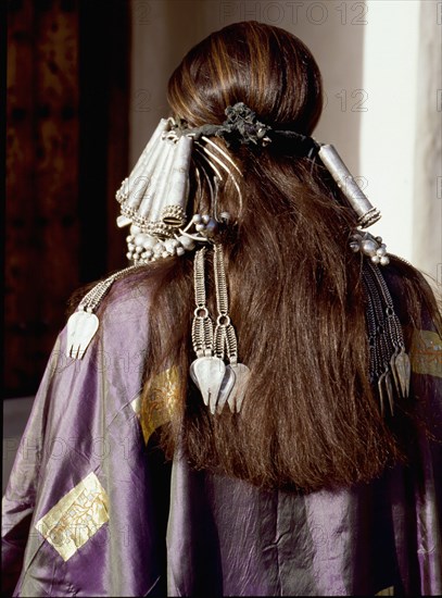 A woman wearing an elaborate silver headdress and traditional costume