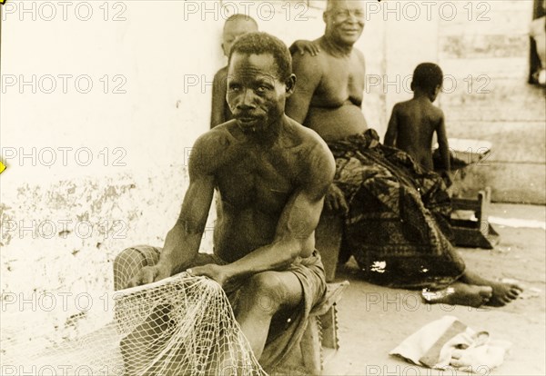 Fisherman repairing his nets, Ghana