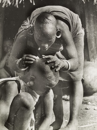 A Kikuyu mother de-louses her daughter