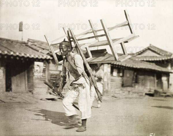 A Korean labourer carries a bench