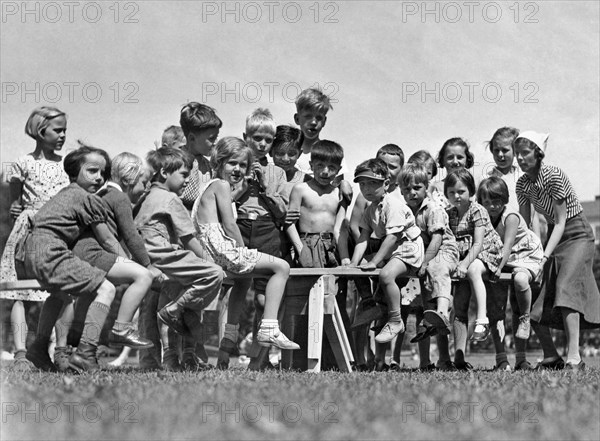 A group of children at a playground balance on a teeter totter