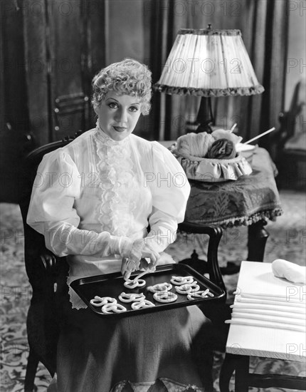 United States:   c. 1920.
A woman making pretzels on a baking sheet for baking.