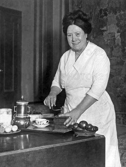 United States: c. 1925.
A woman in a home preparing to serve coffee.