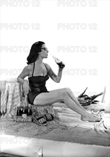 United States: c. 1947.
A set for a photo shoot for a Coca Cola ad, complete with beach sand and a pretty woman in a bathing suit.