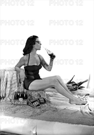 United States: c. 1947.
A set for a photo shoot for a Coca Cola ad, complete with beach sand and a pretty woman in a bathing suit.