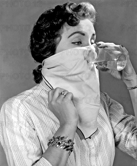 Detroit, Michigan: September 10, 1957.
A young woman tries to cure her hiccups by drinking water through a handkerchief.