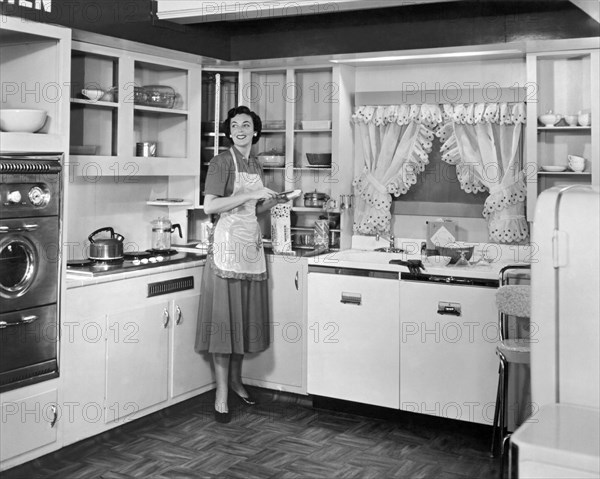 United States: c. 1950. 
A woman wearing an apron in the kitchen of a model home making a sandwich with Wonder Bread.