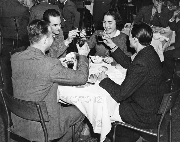 New York, New York:  c. 1939.
Four friends share a toast at a dinner in a restaurant.